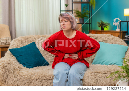 Woman experiencing stomach pain holding belly, uncomfortable painful facial expression showing ache Woman experiencing stomach pain holding belly, uncomfortable painful facial expression showing ache 129227214