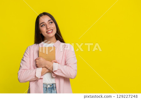Woman smiling closing book pressing it to chest satisfied after reading enjoying emotional story Woman smiling closing book pressing it to chest satisfied after reading enjoying emotional story 129227248