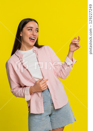 Young woman pretending to play guitar with expressive hand gestures enjoying music with passion joy Young woman pretending to play guitar with expressive hand gestures enjoying music with passion joy 129227249