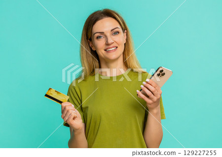 Woman holding smartphone credit card making online purchase clicking order with focused expression Woman holding smartphone credit card making online purchase clicking order with focused expression 129227255