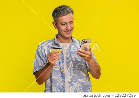 Man holding smartphone and credit card focused while typing payment details for online purchase Man holding smartphone and credit card focused while typing payment details for online purchase 129227259
