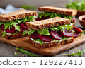 Healthy beetroot sandwiches with goat cheese and arugula on wooden cutting board 129227413
