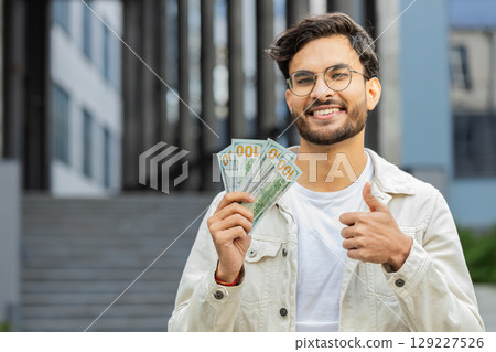 Happy successful rich Indian man counting money cash dollars salary profit reward bribe jackpot 129227526