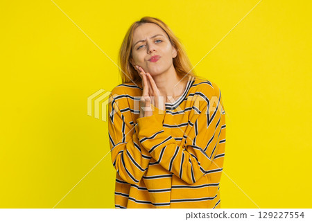 Young woman touching cheek closing eyes with expression of terrible suffer from painful toothache 129227554