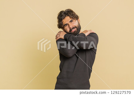Portrait of young Indian handsome man spread hands and give hug to you against beige background 129227570