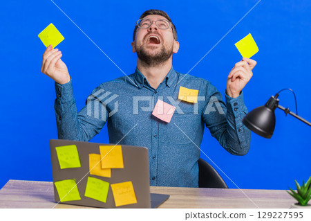 Nervous man with pasted sticker notes use laptop having concentration problem big routine work 129227595