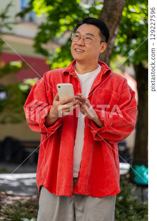 Asian middle-aged man using smartphone typing text messages in social media application online Asian middle-aged man using smartphone typing text messages in social media application online 129227596
