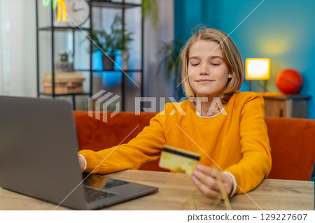 Teenager boy planning online purchase on laptop entering credit card details and ordering from home Teenager boy planning online purchase on laptop entering credit card details and ordering from home 129227607