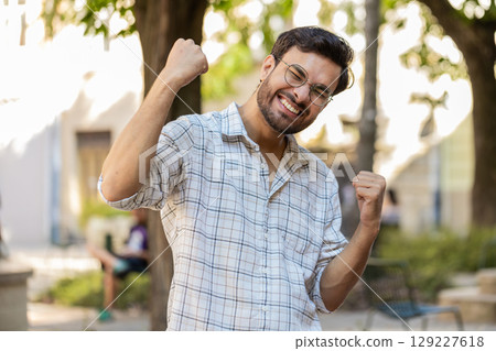 Excited happy man traveler shouting, celebrating success, winning clenching fists walking on street 129227618