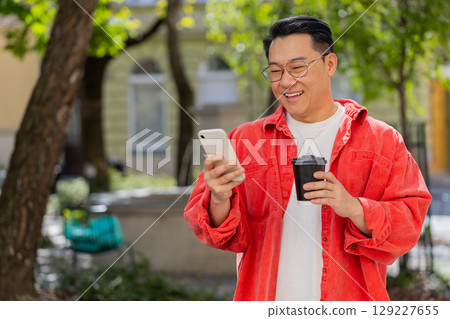 Asian middle-aged man using smartphone typing text messages in social media application online Asian middle-aged man using smartphone typing text messages in social media application online 129227655