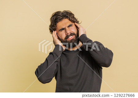 Lebanese bearded man in long sleeves rubbing temples to cure headache problem on beige background Lebanese bearded man in long sleeves rubbing temples to cure headache problem on beige background 129227666
