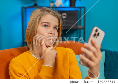Thoughtful teenager boy solving playing puzzle game on smartphone rejoices finding solution at home 129227735