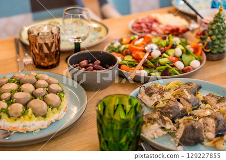 Cose-up of a festive Christmas dinner spread on a wooden table. Homemade dishes Cose-up of a festive Christmas dinner spread on a wooden table. Homemade dishes 129227855