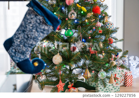 Christmas stocking hanging near a beautifully decorated tree Christmas stocking hanging near a beautifully decorated tree 129227856