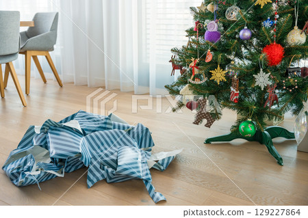 Joy and waste after gift unwrapping near plastic Christmas tree in modern festive living room. Joy and waste after gift unwrapping near plastic Christmas tree in modern festive living room. 129227864