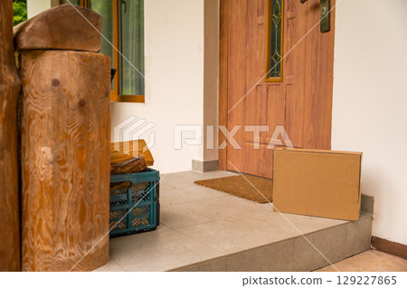 A cardboard box left at the entrance of a wooden country house on a summer day A cardboard box left at the entrance of a wooden country house on a summer day 129227865