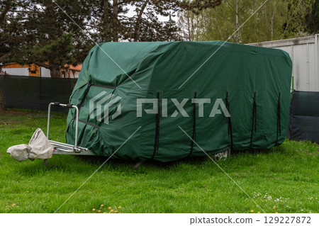 Green protective cover on parked travel trailer in Nova Zivohost campsite, Czech Republic 129227872