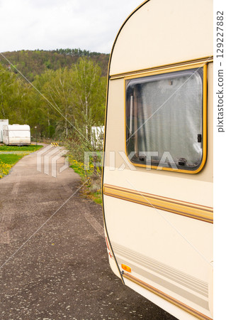 Camper trailer by asphalt road in green campground 129227882