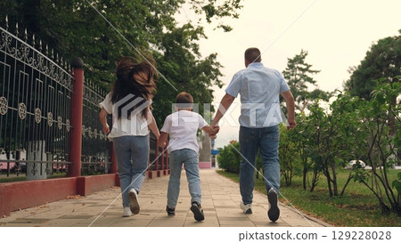 teamwork, three people, three people outdoors, family uniting into team, young family with child son running, group of people running happy green park, boy laughing holding father mother by hand 129228028