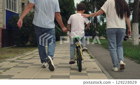 boy laughs smiling sitting bike outdoors, child boy toothless smile, father teaches child kid boy son ride bike outdoors, child kid boy son learns ride bike, child dream of traveling, happy family 129228029