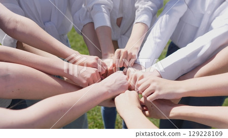A group of hands coming together symbolizes teamwork, unity, and collaboration among diverse individuals. 129228109