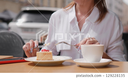 A woman savors a slice of cake and sips rich coffee outdoors, embodying true relaxation and enjoyment 129228135