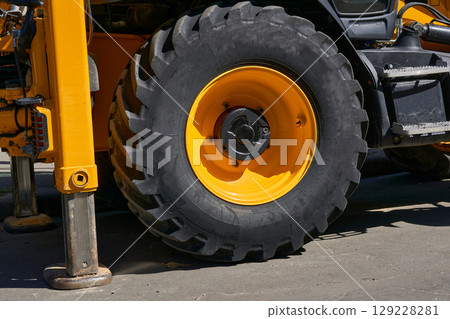 The lifting machine truck crane stands on stops, a large wheel of a tractor The lifting machine truck crane stands on stops, a large wheel of a tractor 129228281