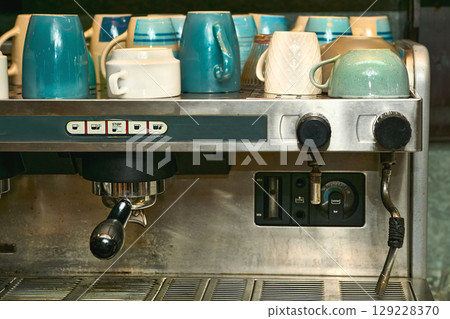 A working, well used coffee machine with different cups in a cafe A working, well used coffee machine with different cups in a cafe 129228370