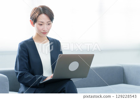在辦公室使用個人計算機的女商人 在辦公室使用個人計算機的女商人 129228543