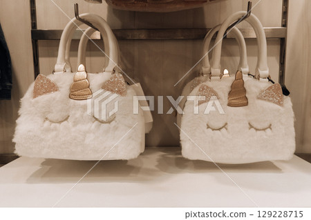 cute fluffy white unicorn bags on shelf in store trendy accessories for children. closeup. cute fluffy white unicorn bags on shelf in store trendy accessories for children. closeup. 129228715