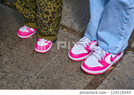 Mother and daughter in identical pink and white sneakers on a walk 129228944