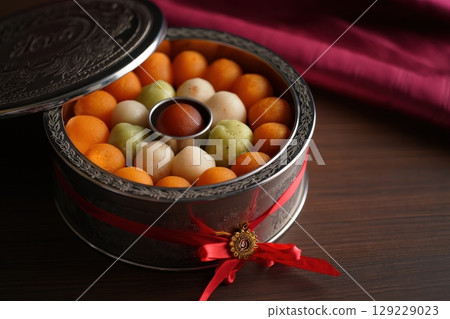 Colorful Indian sweets arranged in round metal box with red ribbon. Diwali Colorful Indian sweets arranged in round metal box with red ribbon. Diwali 129229023