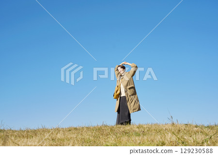 Woman, middle age, stretching, blue sky, whole body Woman, middle age, stretching, blue sky, whole body 129230588