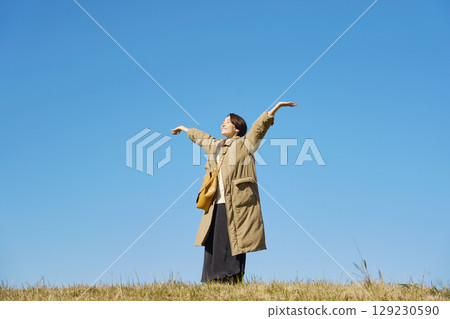 Woman, middle age, stretching, blue sky, whole body Woman, middle age, stretching, blue sky, whole body 129230590