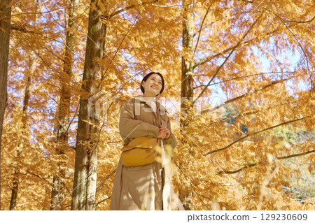 Middle-aged woman walking among autumn leaves Middle-aged woman walking among autumn leaves 129230609