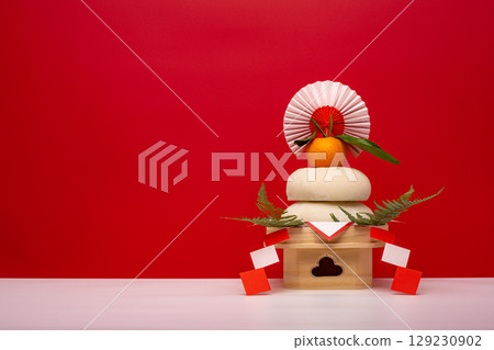 Photo of real rice cake "Kagami-mochi" placed on the right Red and white background with low three treasures (pedestal) Photo of real rice cake "Kagami-mochi" placed on the right Red and white background with low three treasures (pedestal) 129230902
