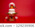A photo of "Kagami mochi" placed on the left, with a red background and a high pedestal. 129230906