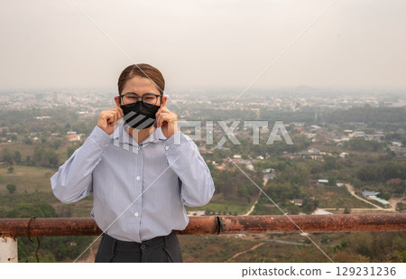 Asian businesswoman wearing N95 mask for protect Bad air pollution (PM2.5). PM2.5 levels meaning the air quality posed a health hazard. Asian businesswoman wearing N95 mask for protect Bad air pollution (PM2.5). PM2.5 levels meaning the air quality posed a health hazard. 129231236