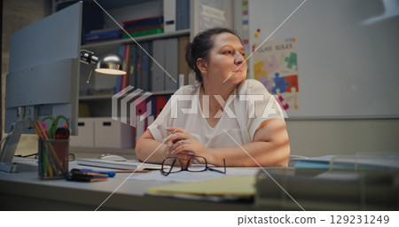 Tired Female Teacher Sitting at Computer in Empty Classroom, Feeling Stress, Burnout Tired Female Teacher Sitting at Computer in Empty Classroom, Feeling Stress, Burnout 129231249