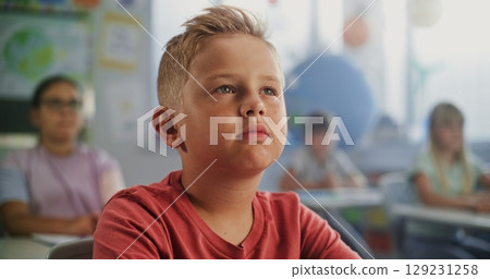 Close Up of Elementary School Boy Sitting at the Desk, Listening to Lecture from Teacher Close Up of Elementary School Boy Sitting at the Desk, Listening to Lecture from Teacher 129231258