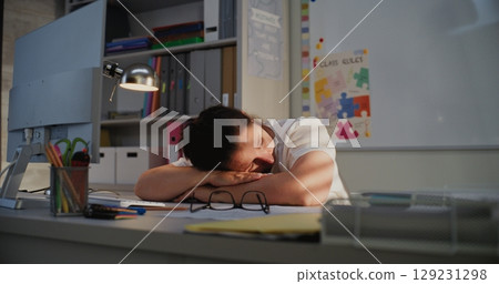 Exhausted Female Teacher Sitting at Computer in Empty Classroom, Feeling Stress Exhausted Female Teacher Sitting at Computer in Empty Classroom, Feeling Stress 129231298