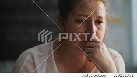 Exhausted Female Teacher Taking Off Glasses, Sitting Alone in Empty Classroom, Feeling Stress Exhausted Female Teacher Taking Off Glasses, Sitting Alone in Empty Classroom, Feeling Stress 129231351