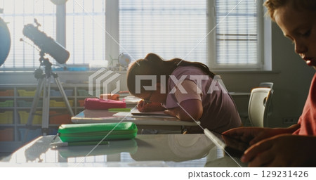 Elementary School Students Sitting at Desks, Studying in Modern Classroom 129231426