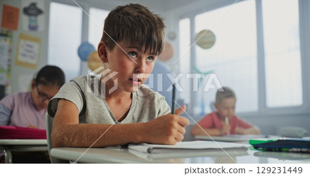 Elementary School Boy Sitting at Desk, Doing Writing Tasks in School Notebook 129231449
