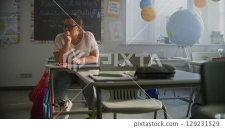 Tired Female Teacher Sitting Alone at the Desk in Empty Classroom, Relaxing After Class Tired Female Teacher Sitting Alone at the Desk in Empty Classroom, Relaxing After Class 129231529