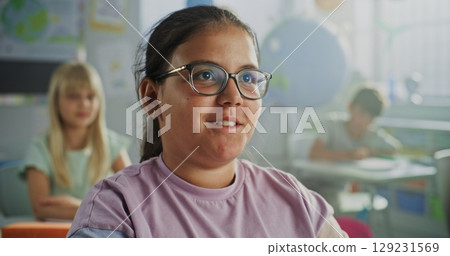 Close Up of Elementary School Girl Raising Hand and Answering Teacher's Question During Geography Lesson 129231569