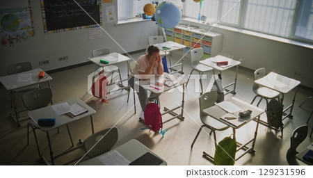Tired Female Teacher Sitting Alone in Empty Classroom, Relaxing After Class 129231596