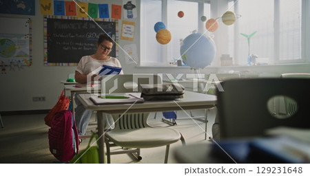Exhausted Female Teacher Sitting Alone at Desk in Empty Classroom, Having Rest After Lesson 129231648