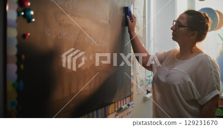 Female Teacher Erasing Classroom Chalkboard, Finishing Psychology Lesson with School Children 129231670