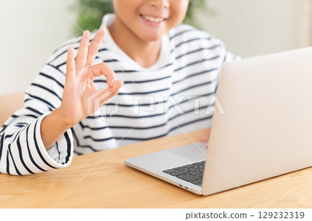 一名小學生在家使用電腦時畫圓圈手勢 一名小學生在家使用電腦時畫圓圈手勢 129232319